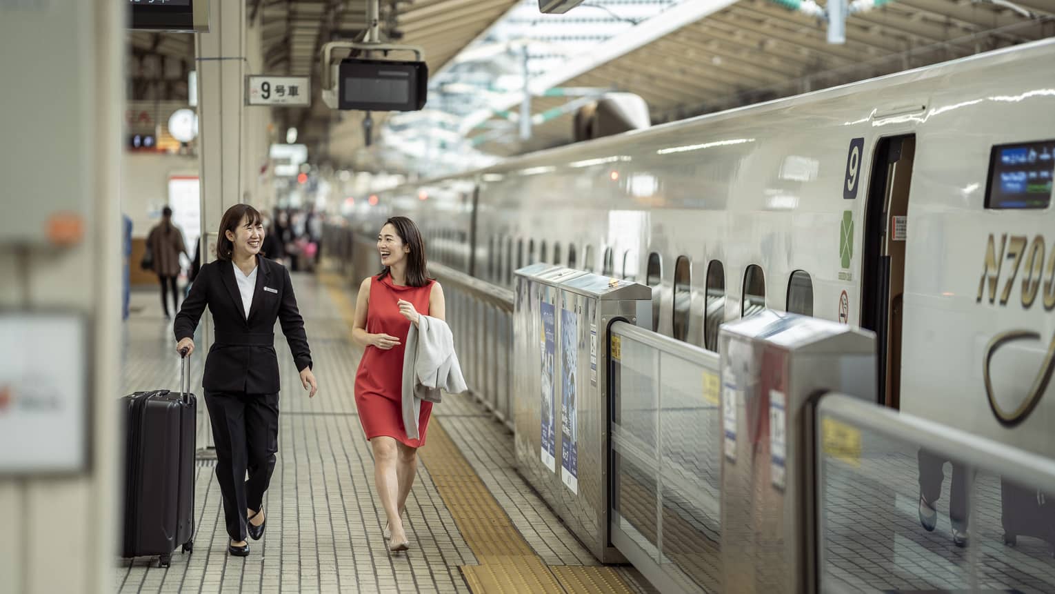 Train station greeter walks with female guest along the train platform