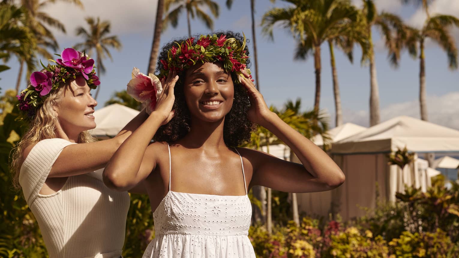 Woman puts a floral lei headpiece on another woman