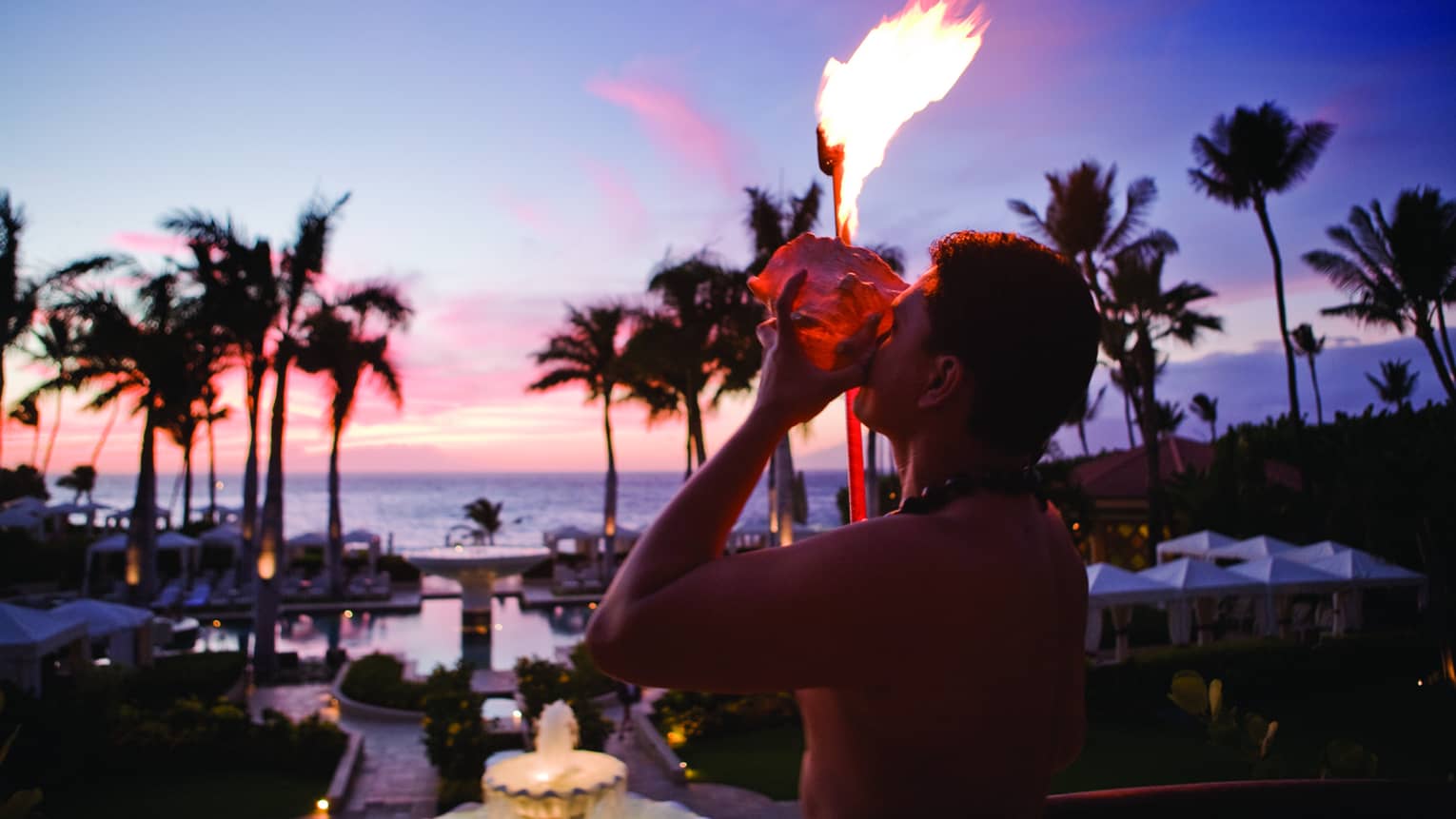 A staff member lights a torch with a view of the ocean