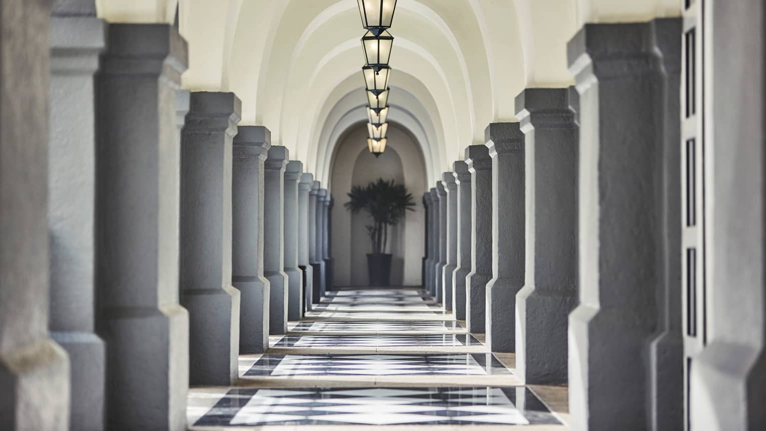 Stone pillars, lanterns down long, sunny outdoor hallway
