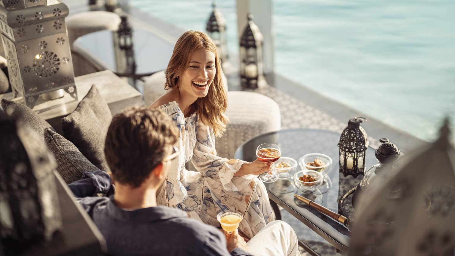 Couple laughs over cocktails poolside at Al Barakat