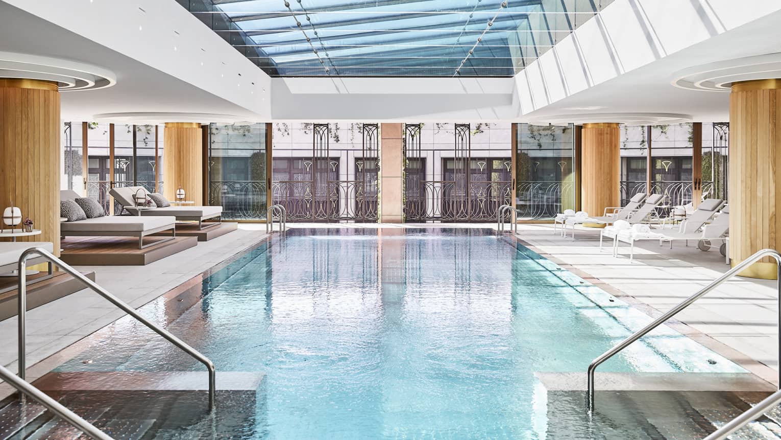 Rectangular indoor pool with two staircases into the pool, glass window ceiling