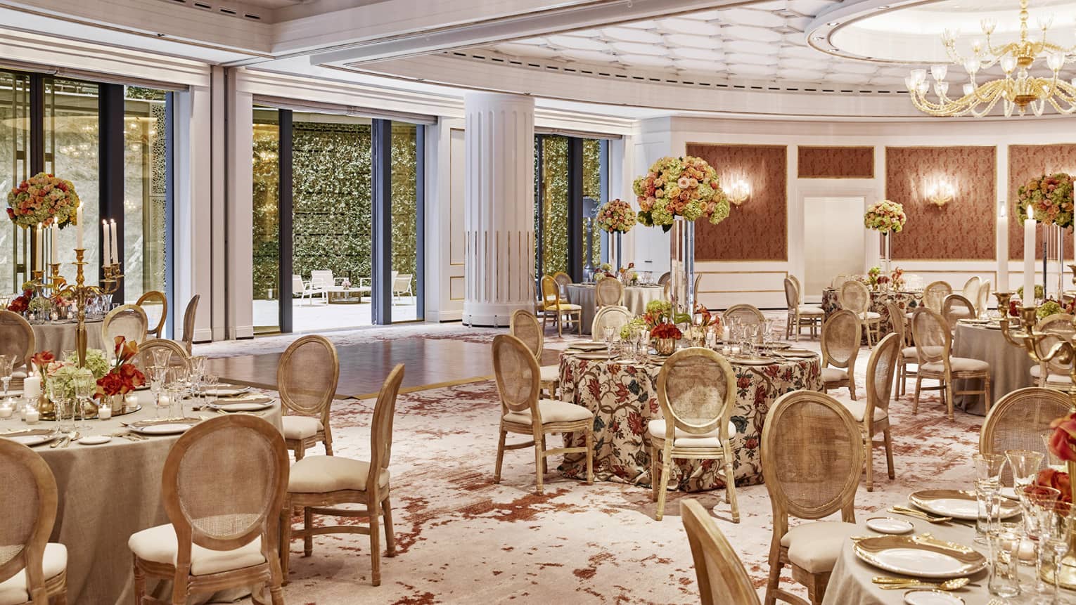 Several tables and chairs adorned with linens, flowers and glassware.