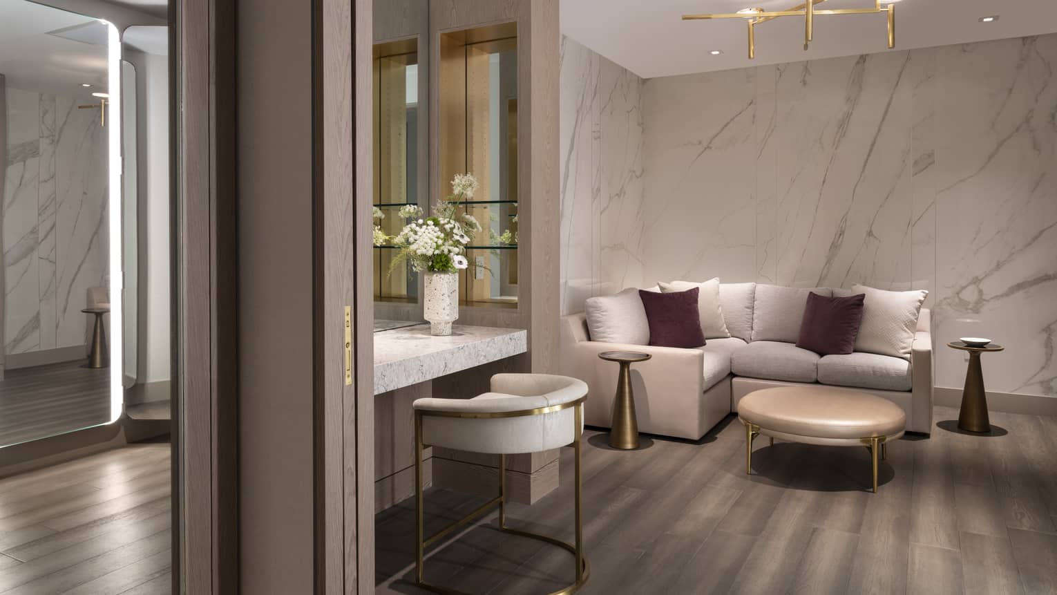 An L-shaped couch, coffee table, mirrors and vanity table fill a corner of the Celebration Suite