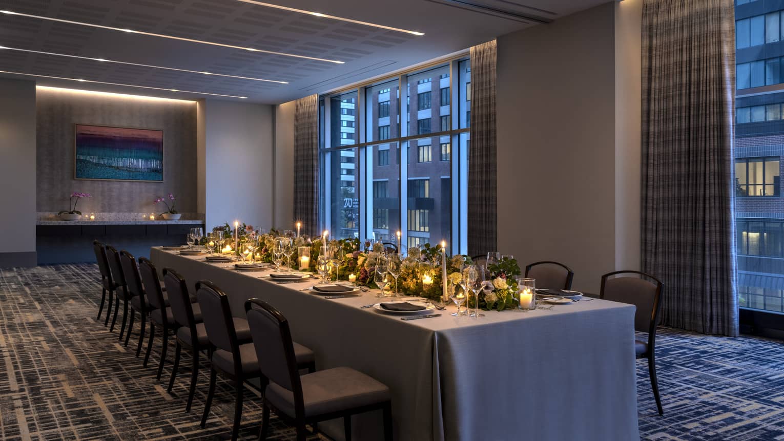A long table with candles and flowers in a dimly lit room.