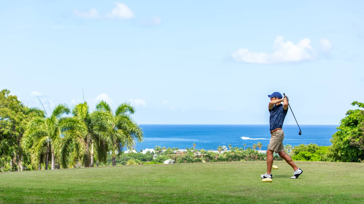 A man golfing near an ocean.