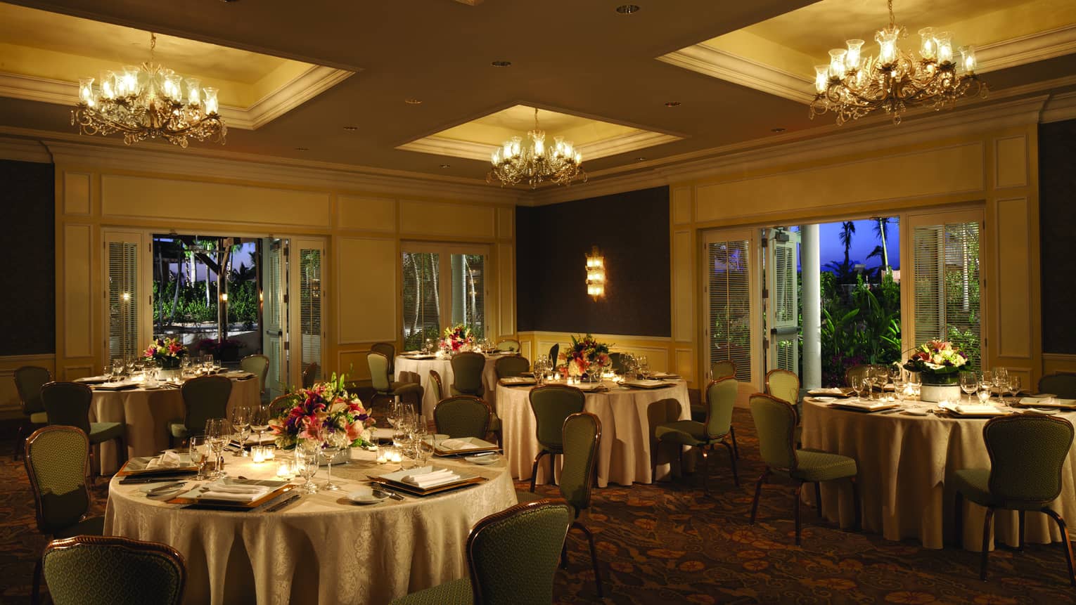 Round candle-lit banquet dining tables in dimly-lit ballroom