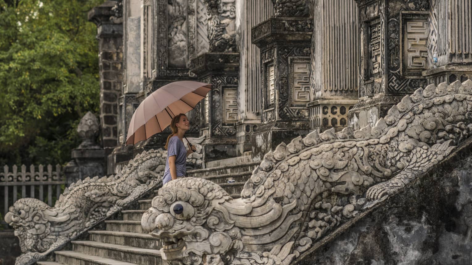 A woman carrying a mauve umbrella, walking up the stone steps of Hue City - Khai Dinh Tomb