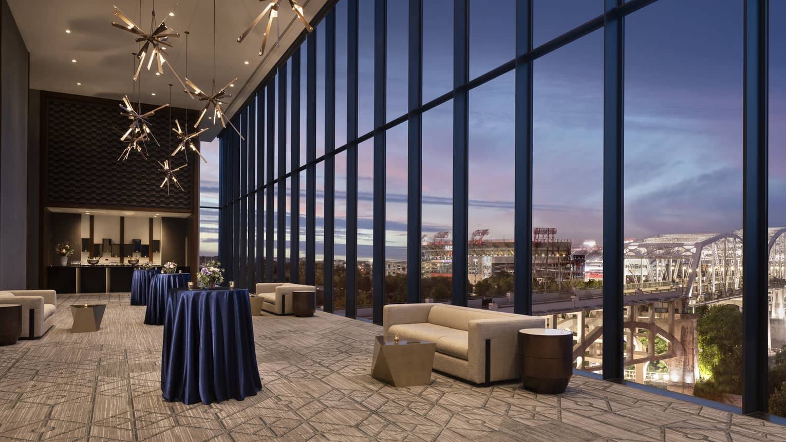 Indoor pre-function space with a wall of windows looking out to Nashville at dusk