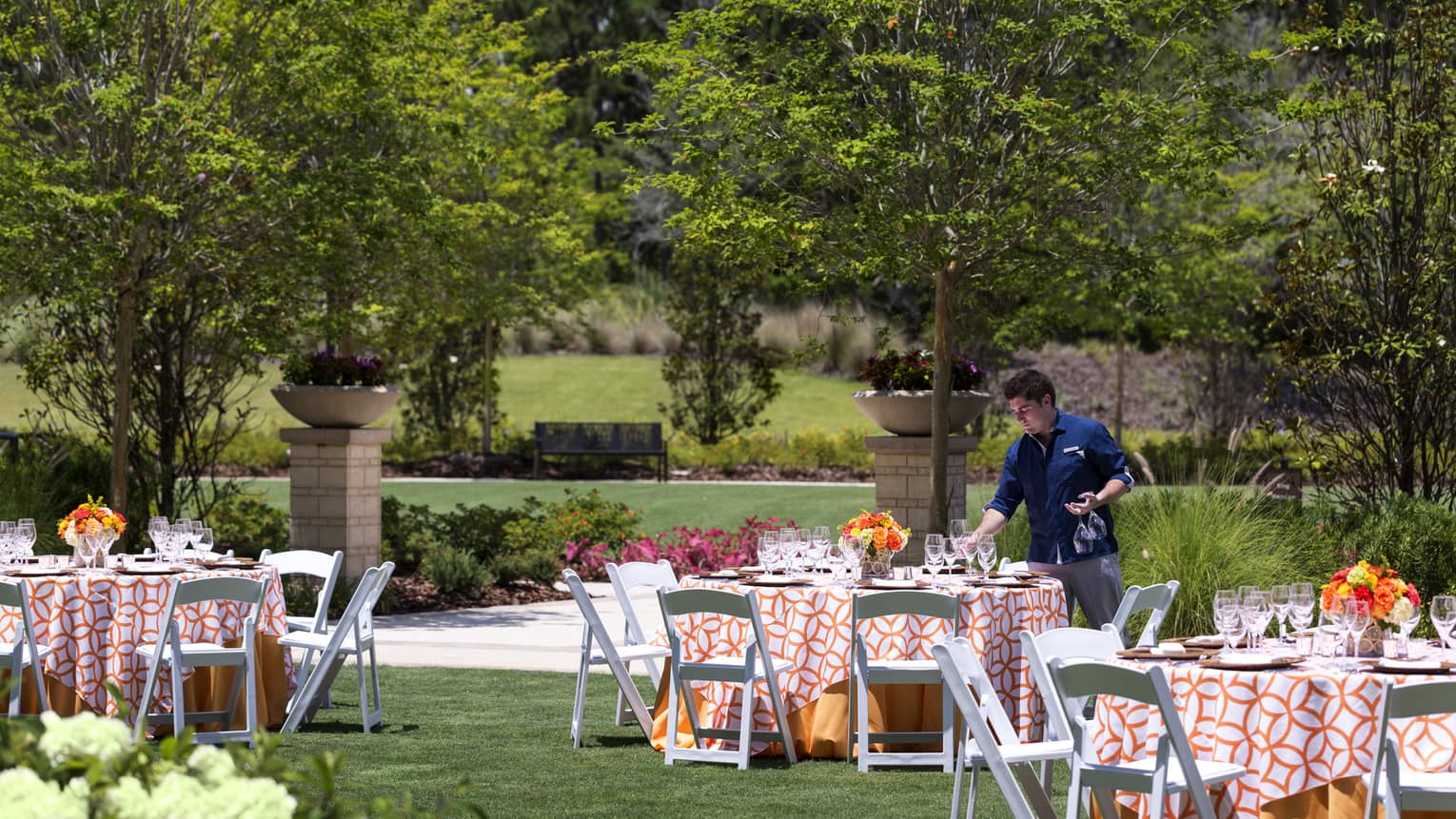 A four seasons server sets tables outside on the lady palm lawn at four seasons resort orlando at walt disney world