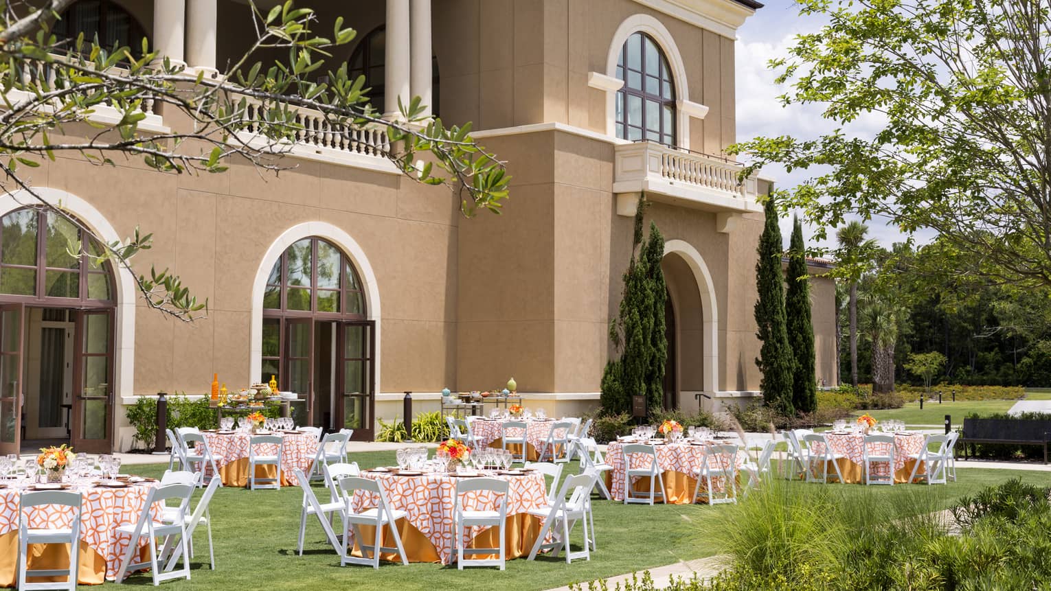 Garden wedding set up, round tables with orange linens, white chairs