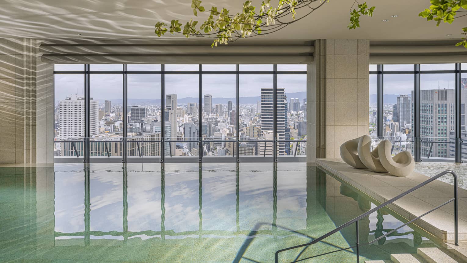 Indoor pool at Four Seasons Hotel Osaka, with wall of windows looking out to Osaka city