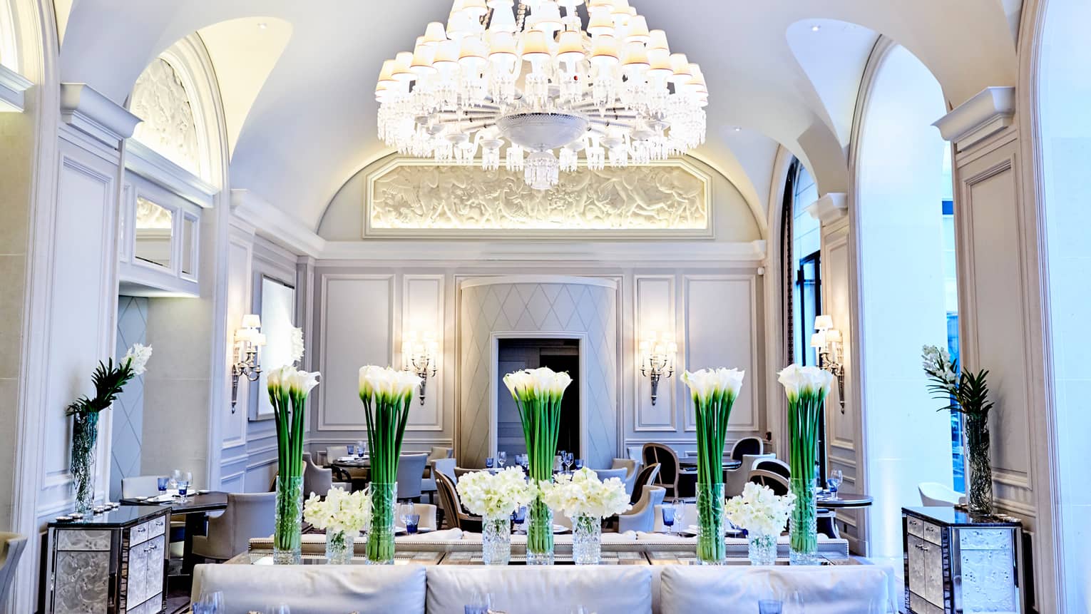 Le George dining room, white flowers in vases under large crystal chandelier