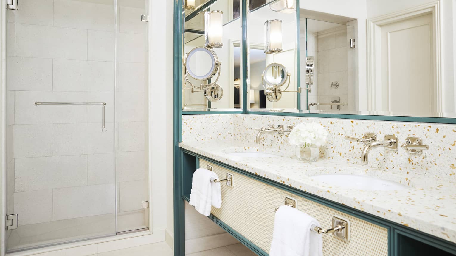 A bright bathroom has metal accents and marble countertops
