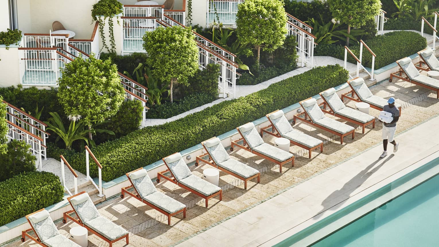 White lounge chairs next to an outdoor pool.