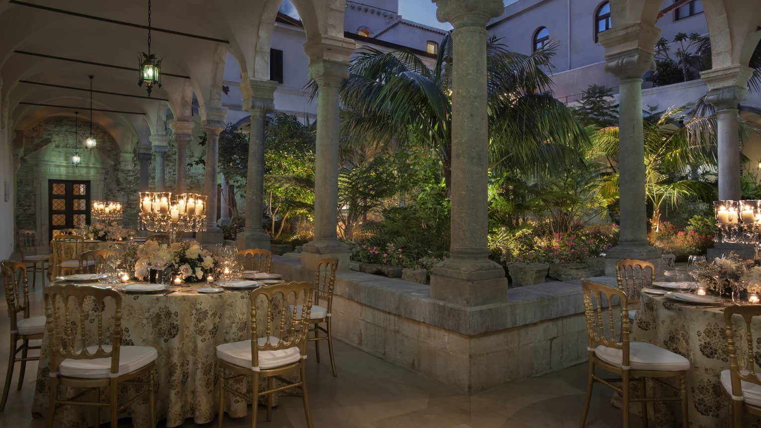 Ancient Cloister outdoor venue with elegant table settings under stone archway at dusk