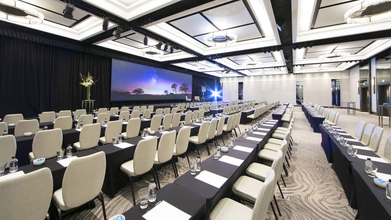 Ballroom meeting space with conference classroom style seating facing a projected screen