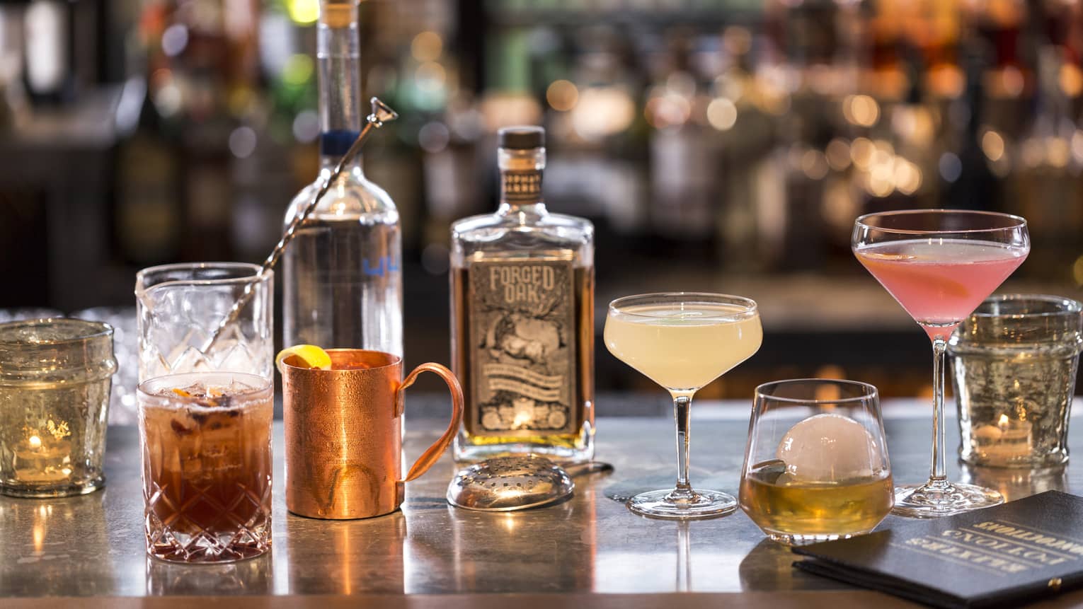 Various cocktails, liquor bottles and shakers on bar 