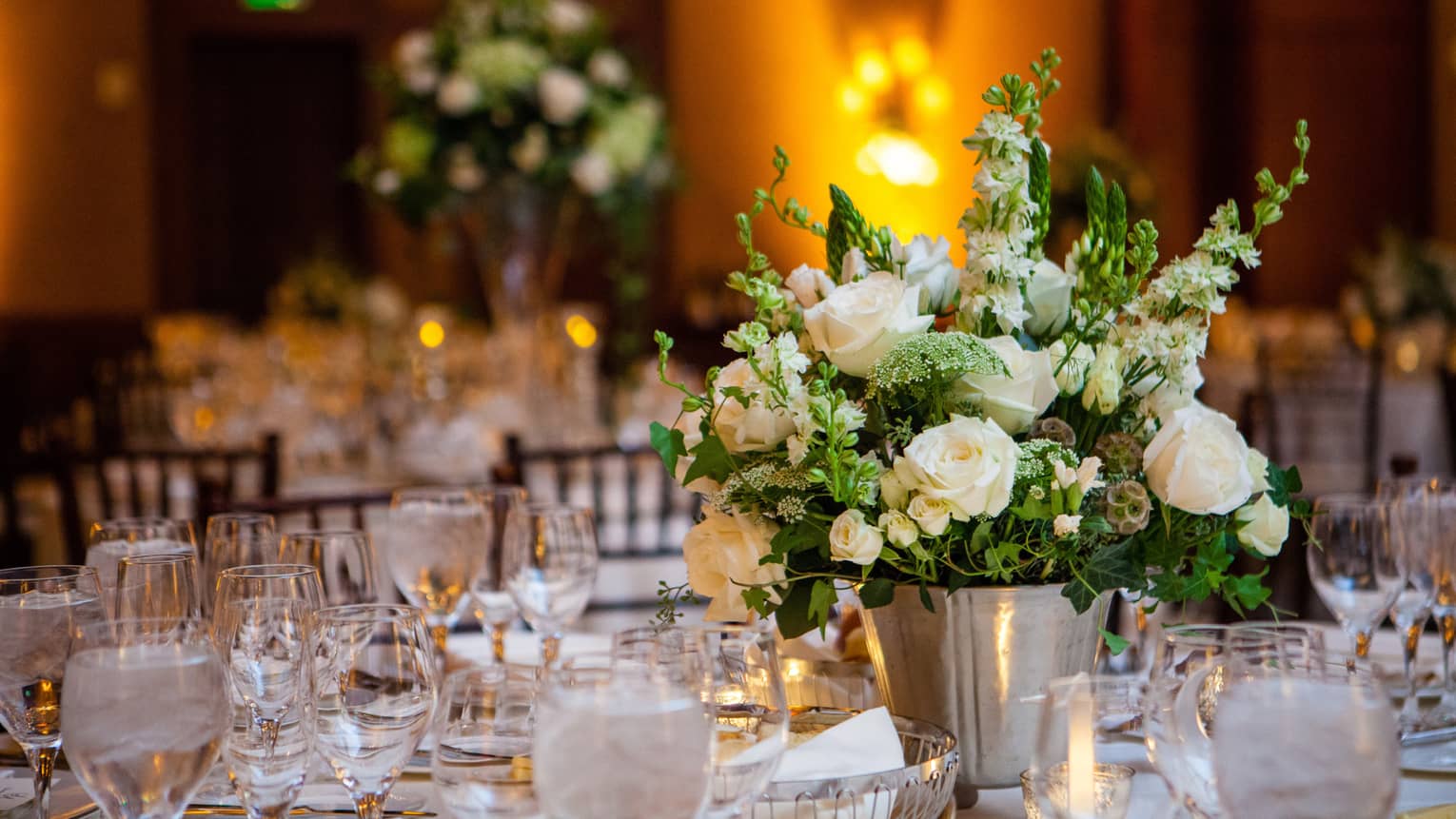 Wedding reception banquet table with glassware, white roses in vase
