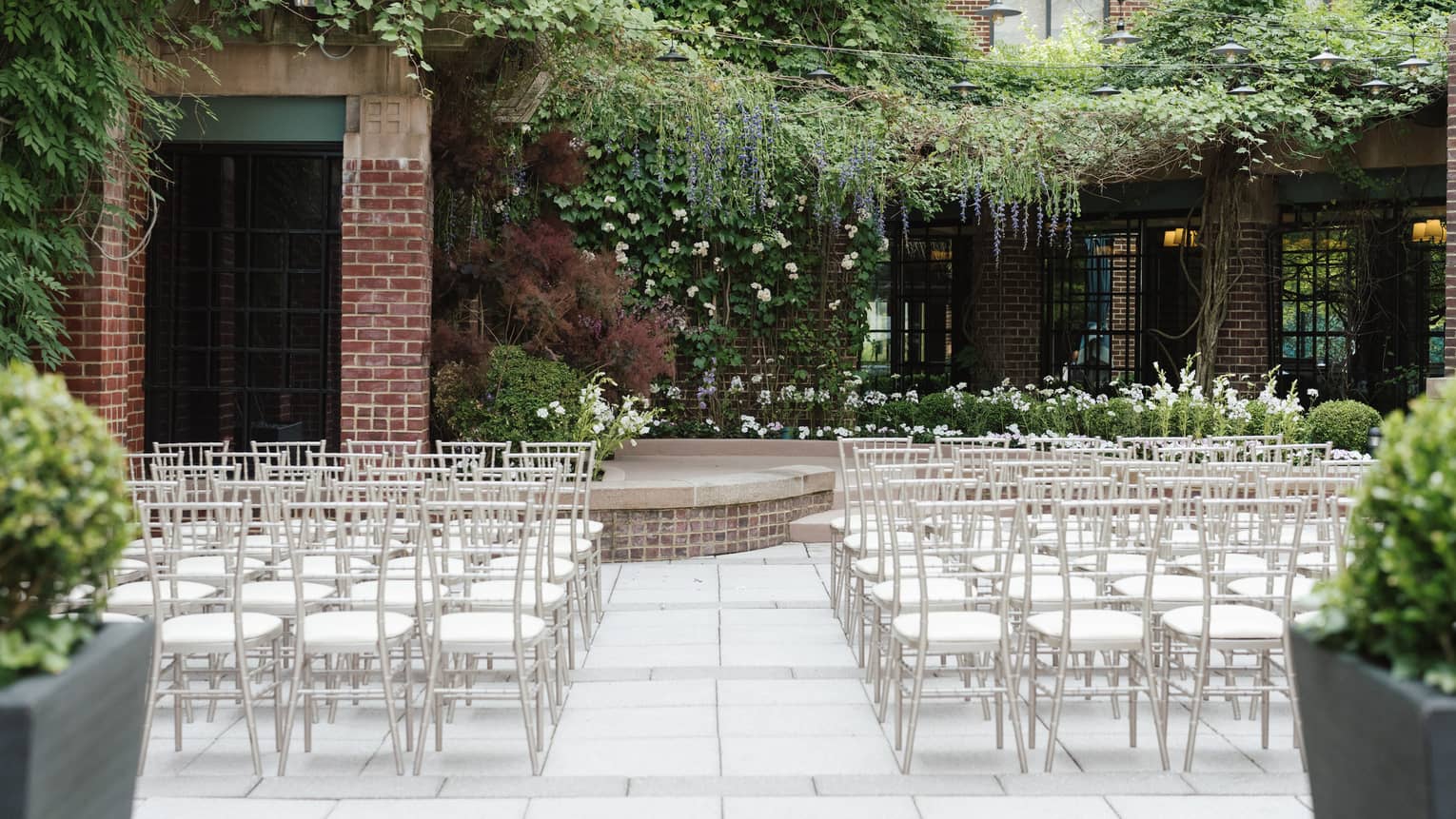 An outdoor venue with rows of white seats and greenery.