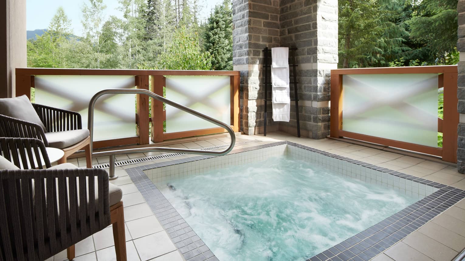 Luxurious private outdoor hot tub on the balcony of the Townhouse Suite at Four Seasons Whistler. The hot tub is surrounded by modern wood and glass railings that offer privacy while allowing views of the lush green forest surrounding the property. The area is equipped with dark wood lounge chairs for relaxation and a stone pillar that supports outdoor lighting, enhancing the serene and exclusive atmosphere.,Luxurious private outdoor hot tub on the balcony of the Townhouse Suite at Four Seasons Whistler. The hot tub is surrounded by modern wood and glass railings that offer privacy while allowing views of the lush green forest surrounding the property. The area is equipped with dark wood lounge chairs for relaxation and a stone pillar that supports outdoor lighting, enhancing the serene and exclusive atmosphere.