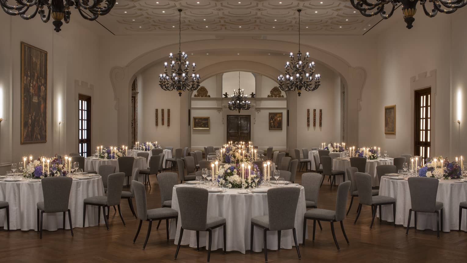 Grand Chiesa Ballroom elegantly set with round clothed tables under large chandeliers