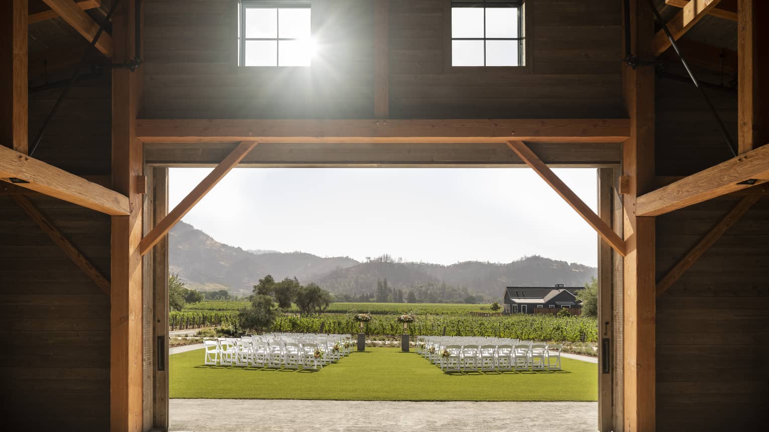 Barn doors opening up to lawn set up for wedding ceremony