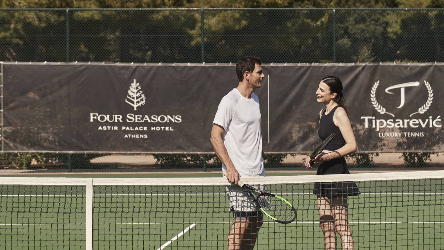 A man and woman holding tennis rackets on a court.