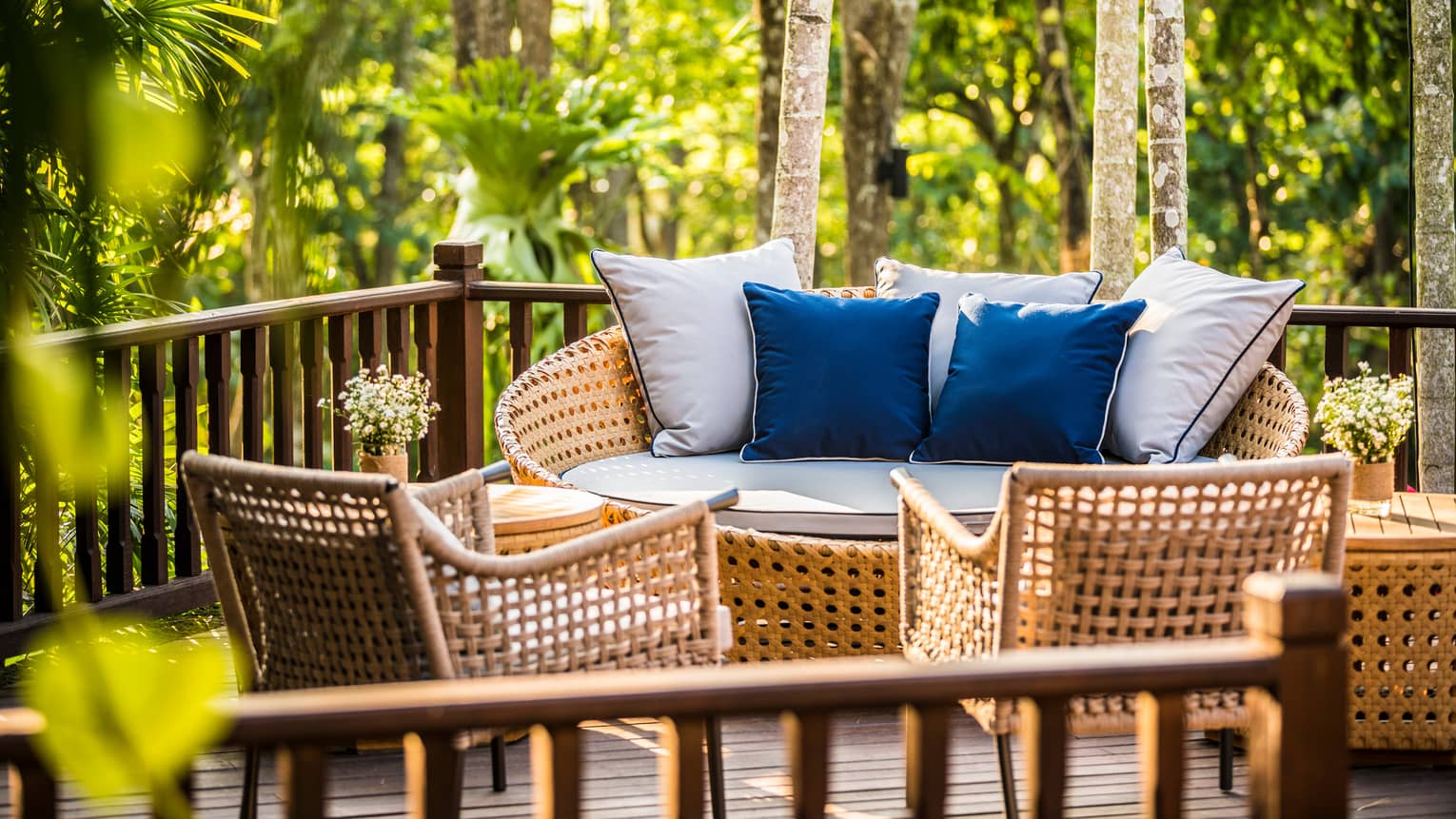 Wicker loveseat with white and blue cushions across from chairs on patio