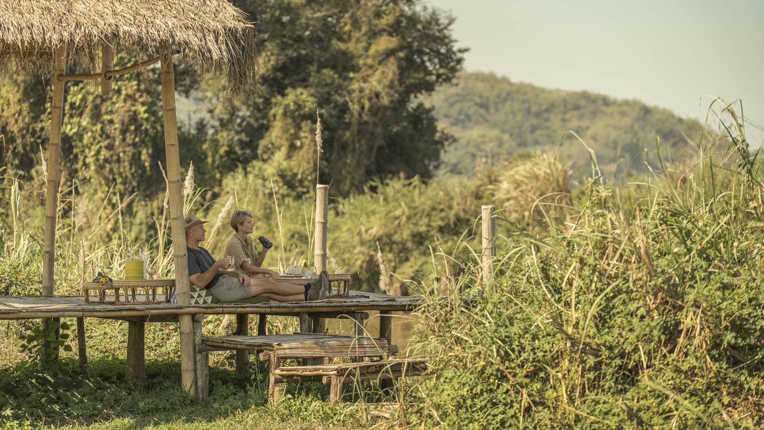 Couple enjoys a camp picnic with views of Thailand's rolling green hills