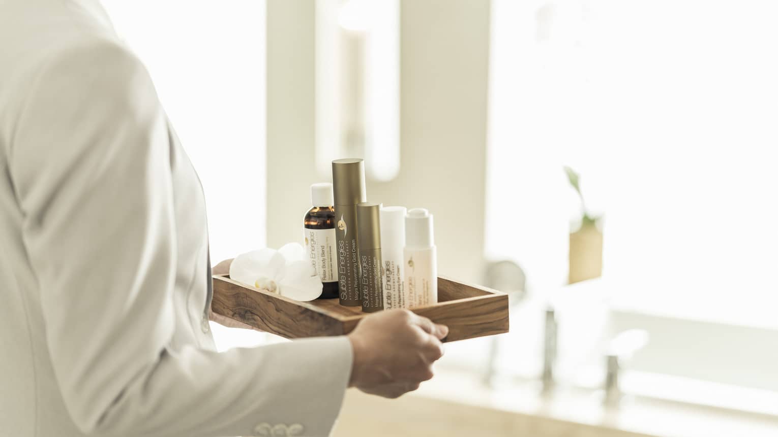 hotel staff carrying tray of spa products