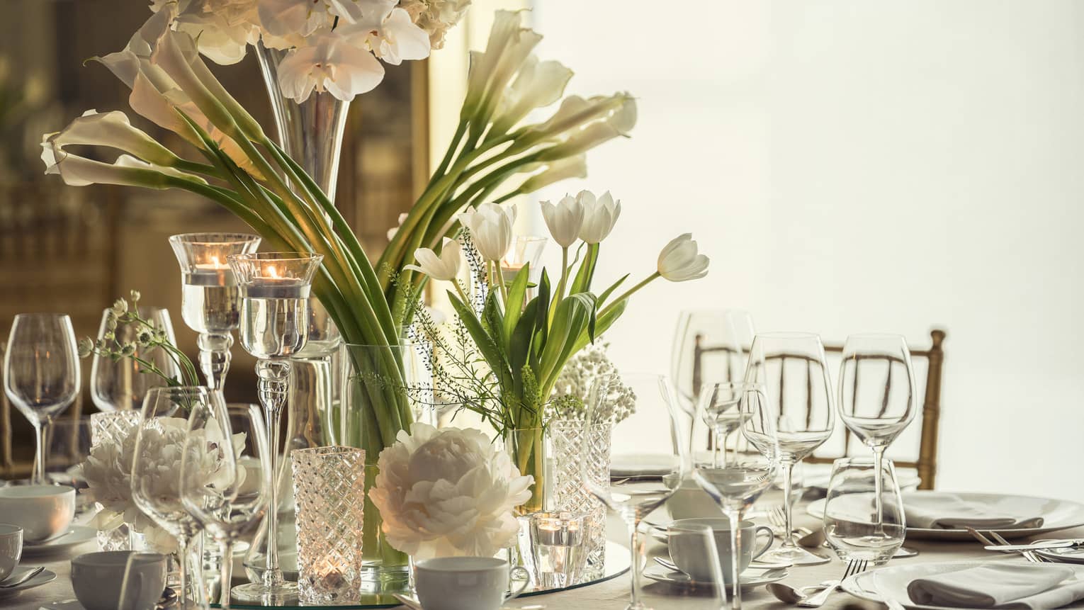 Western Banquet room dining table with glassware, long stemmed white flowers in vase