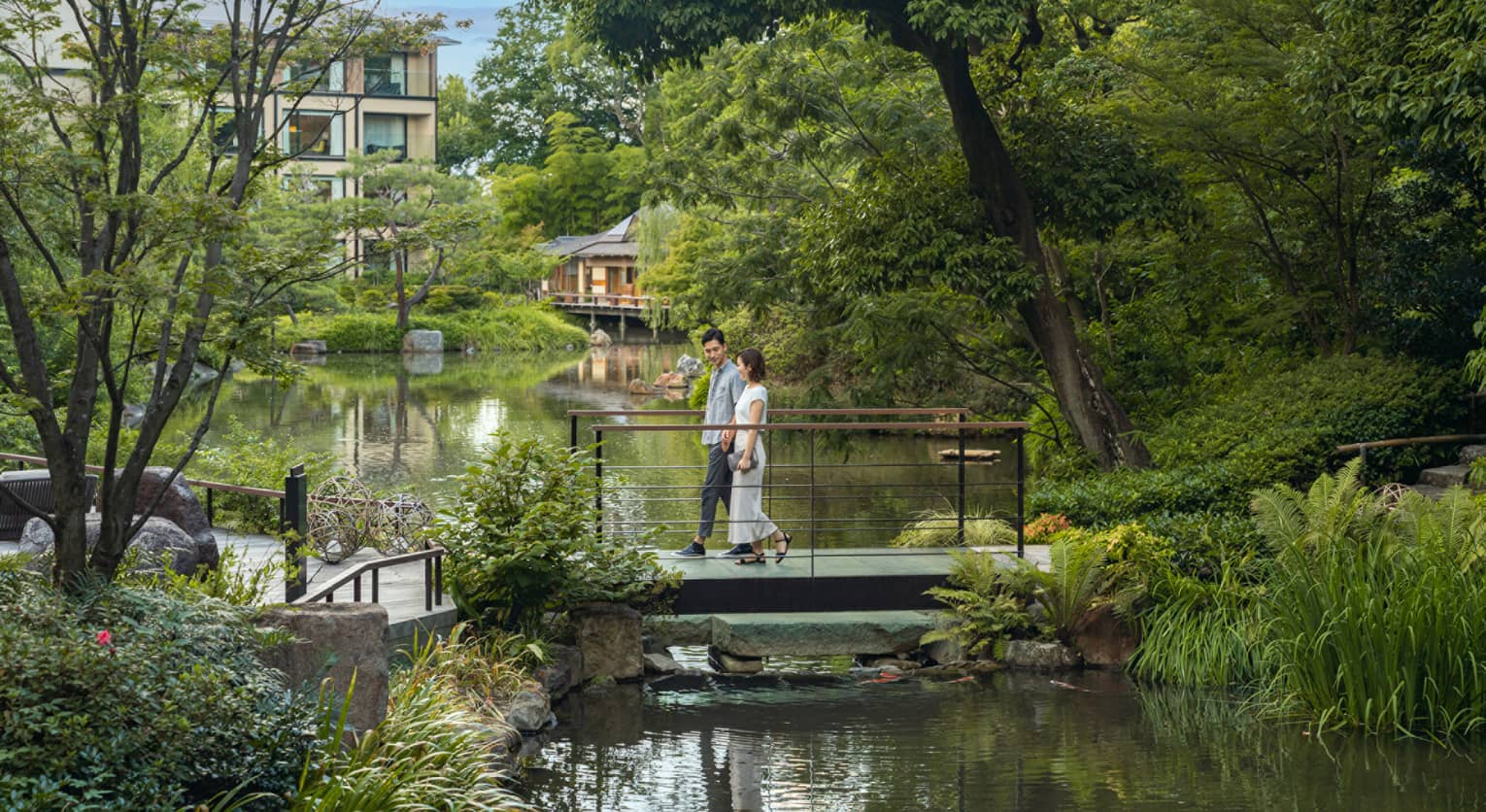Couple walks across foot bridge over koi pond