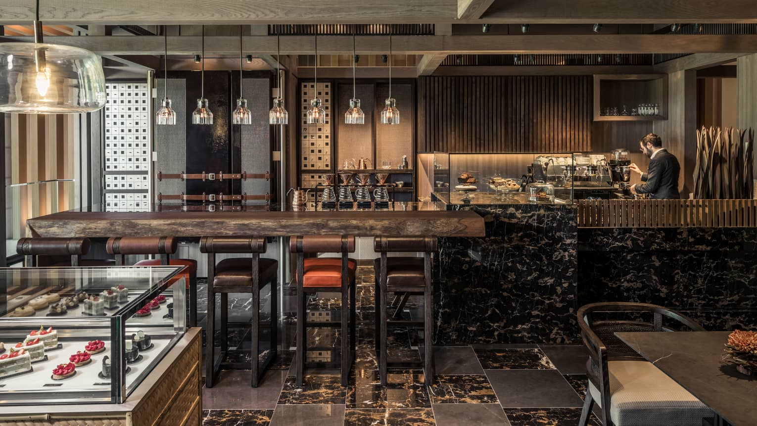 The Lounge rustic wood and black marble bar lined with leather stools, glass display with desserts
