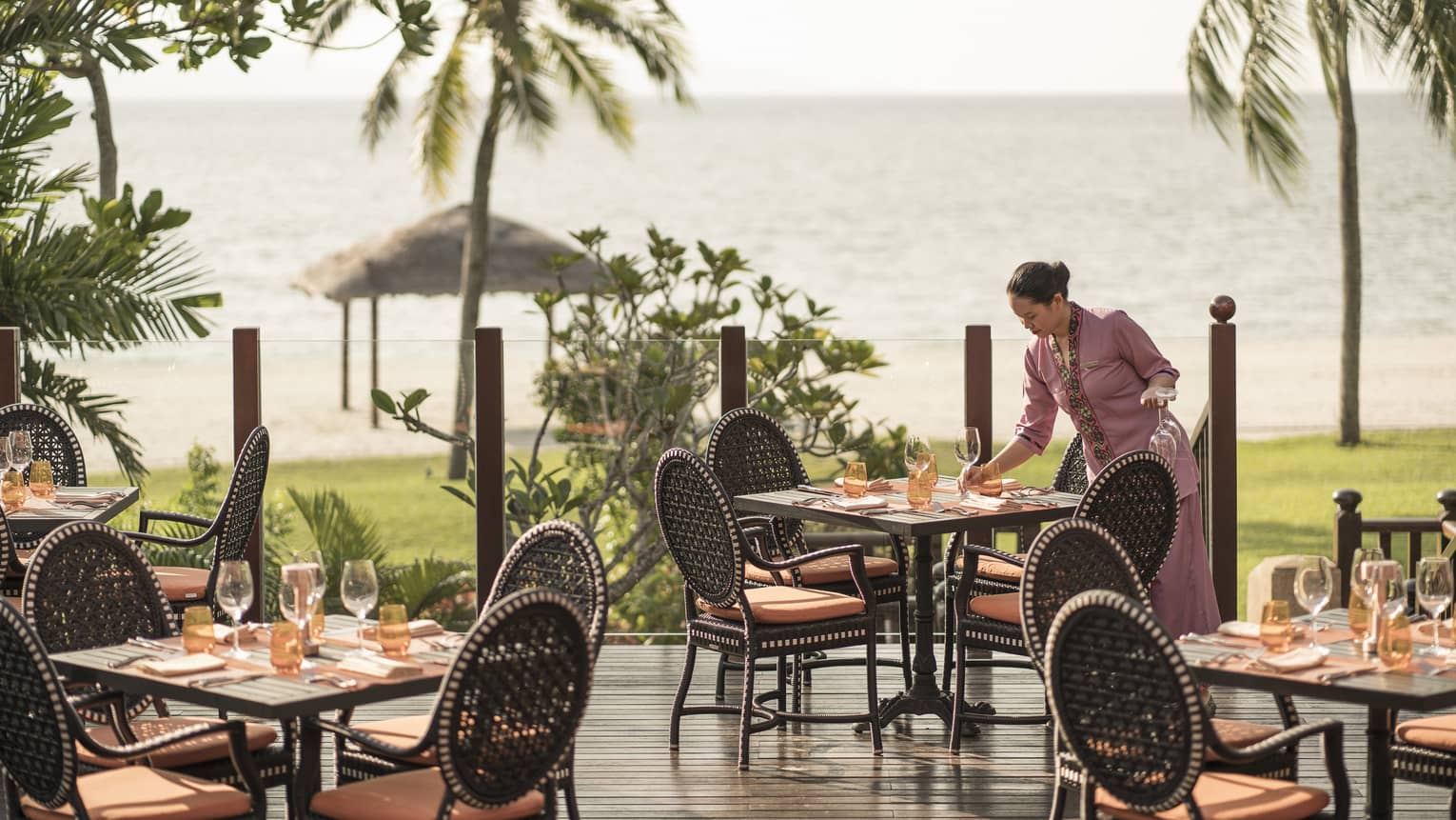 A server at Ikan Ikan sets a table on the outdoor terrace overlooking the beach