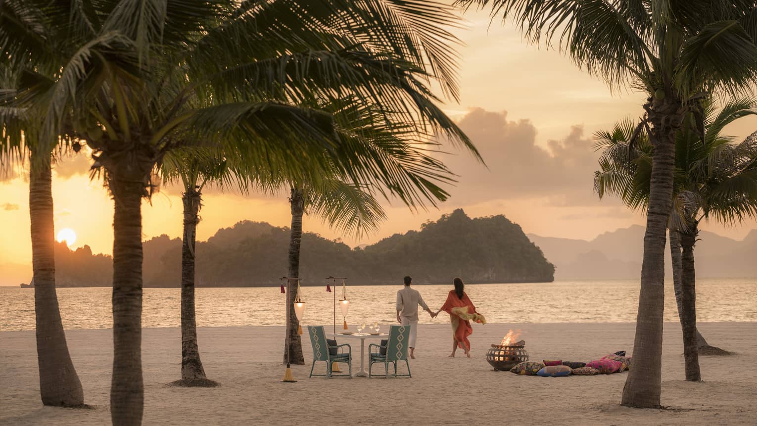 A man and woman on a beach having a Punta chintai private dinner at Four Seasons Langkawi