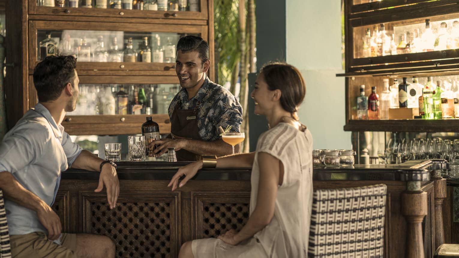 Two guests chat with a bartender at rhu bar while he makes a drink