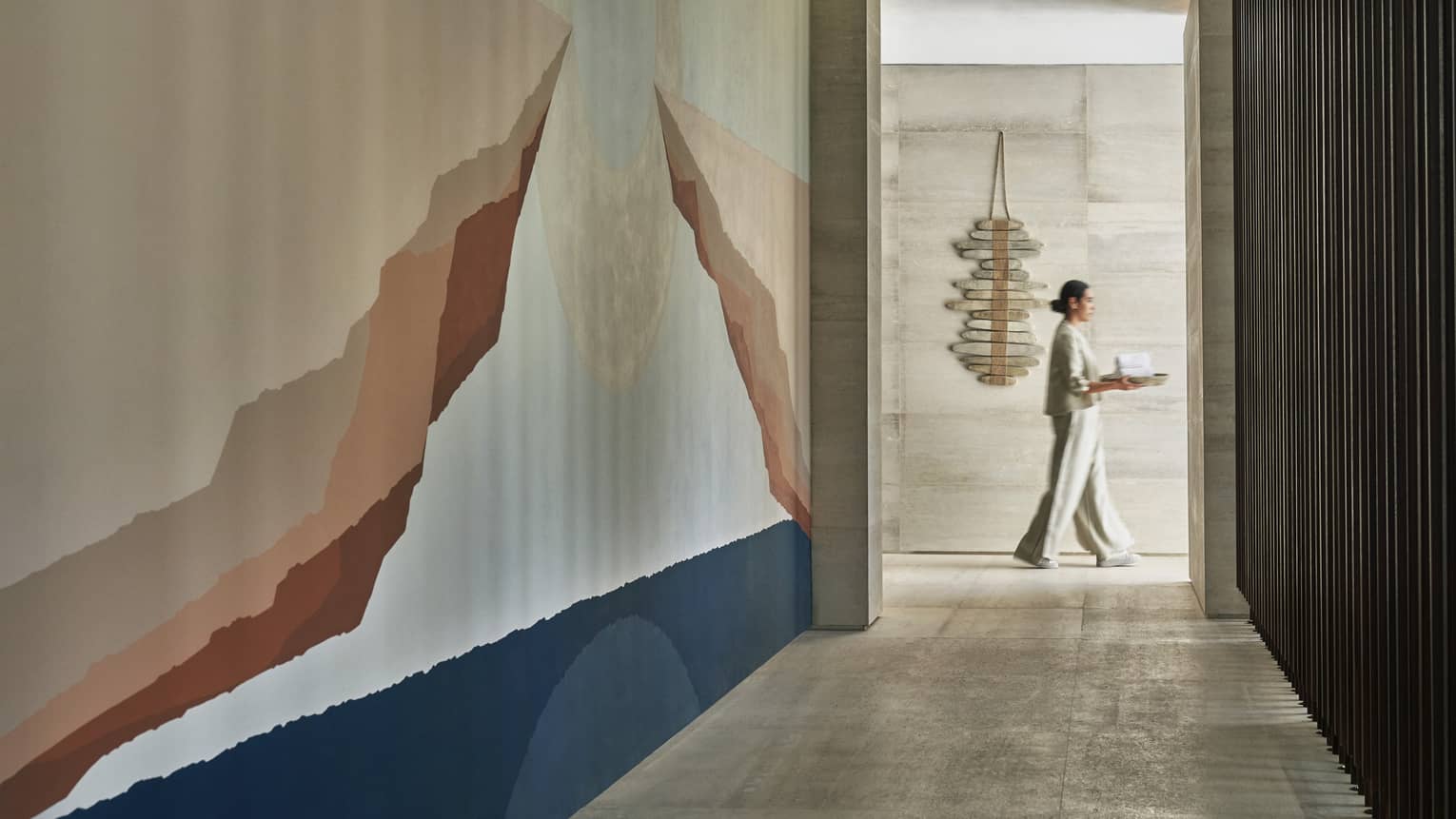 A four seasons spa staff carries a tray through a white marble corridor 