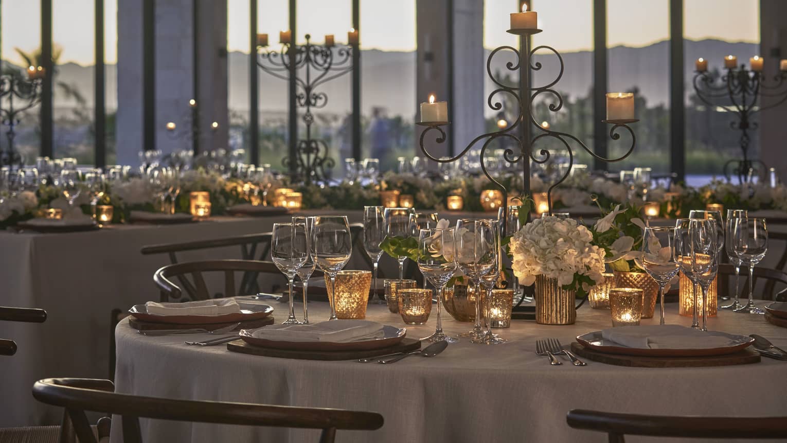Floor to ceiling paneled windows let in the evening light into the glamorous ballroom, decorated with candles, white floral arrangements and crystal dinnerware.  