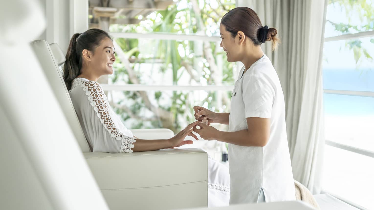 A four seasons guest gets her nails down while sitting in a white leather salon chair 