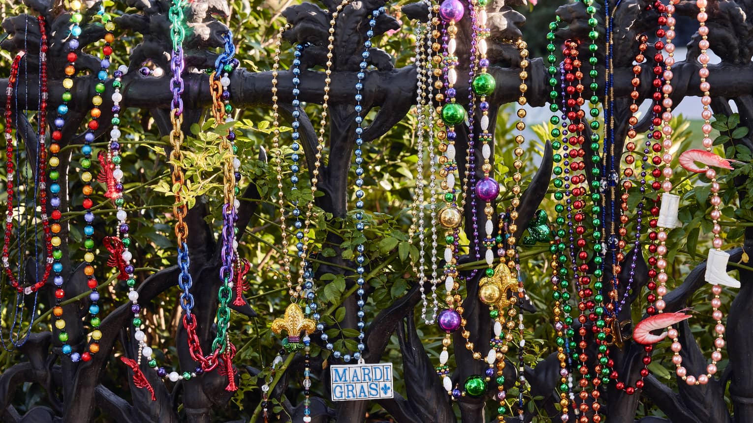Strands of colourful Mardi Gras beads hanging on a wrought iron post