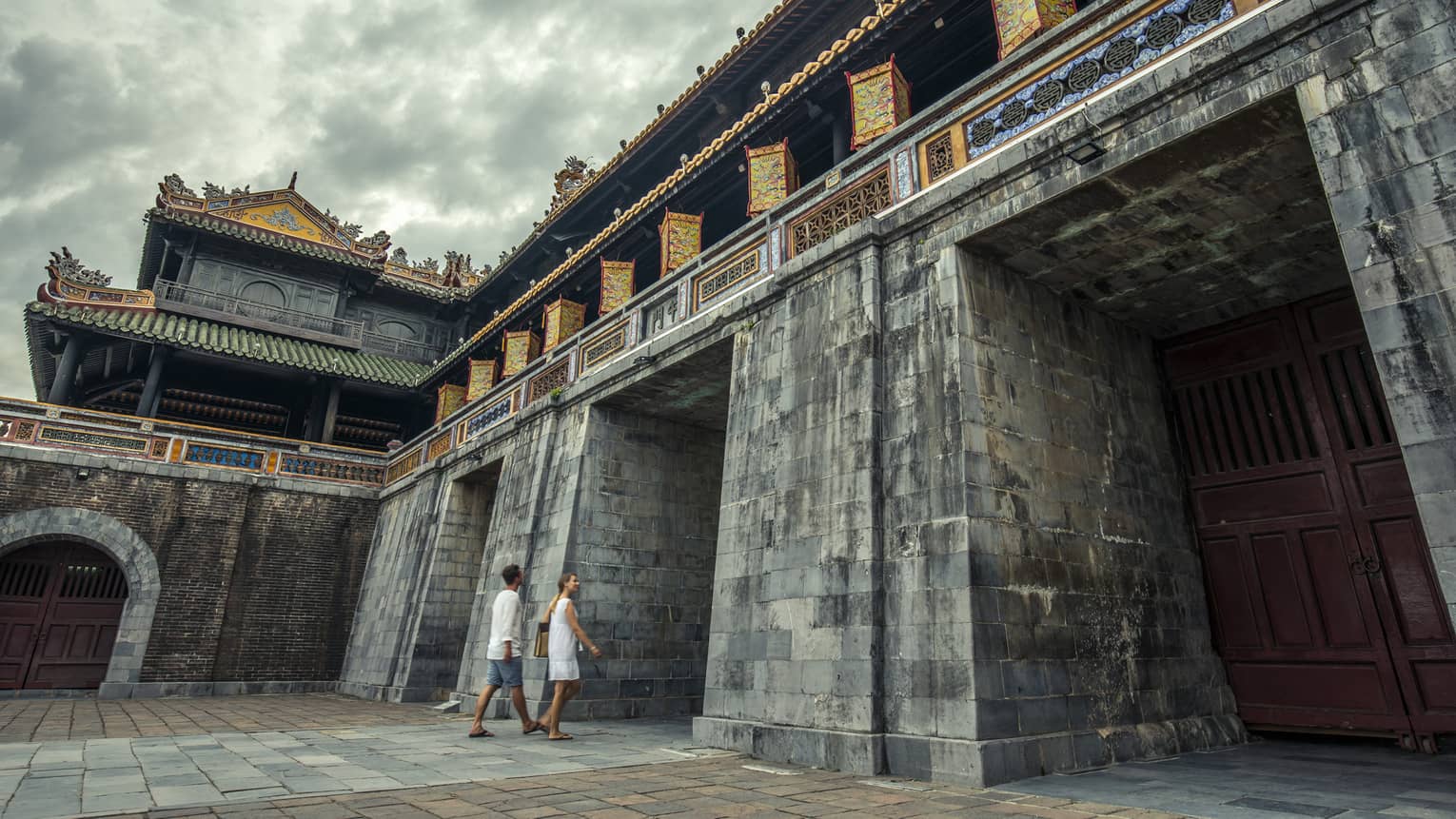 A man and woman walking through the ornate structure of Hue City - Imperial City