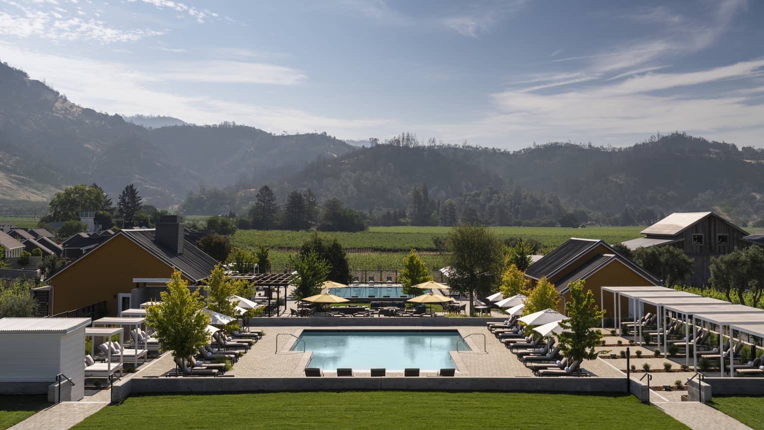 Resort pool in Napa Valley, lined with lounge chairs and mountains in distance