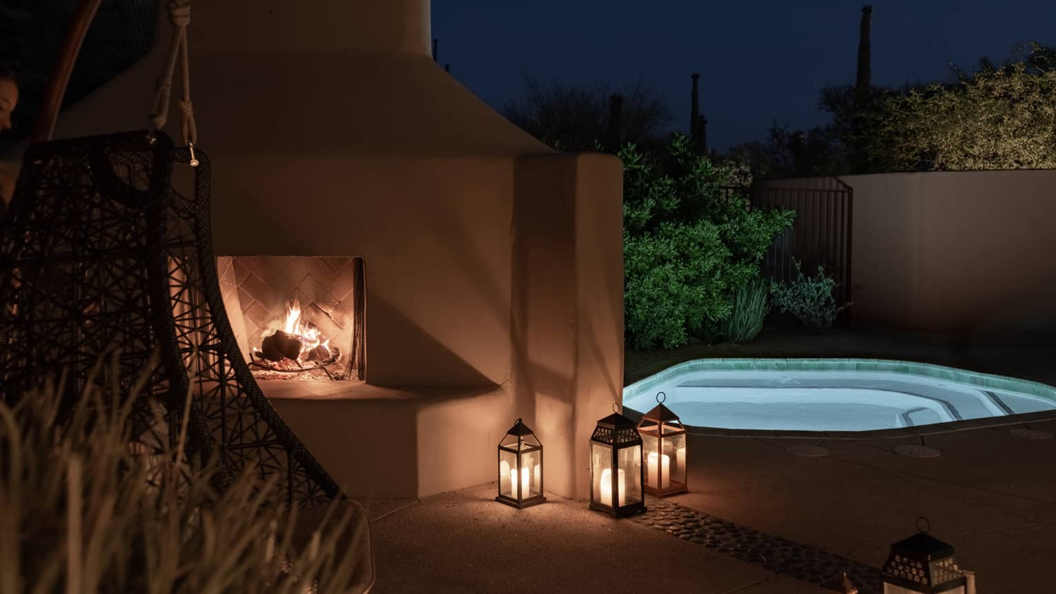An outdoor fireplace and plunge pool at night.