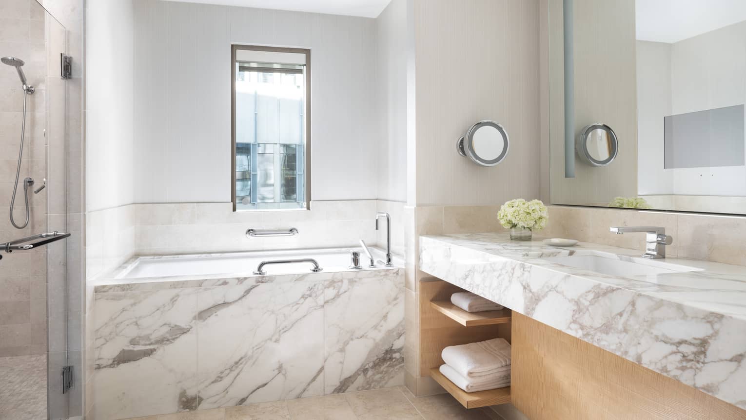 Marble counter and a marble bathtub gleam in a bathroom