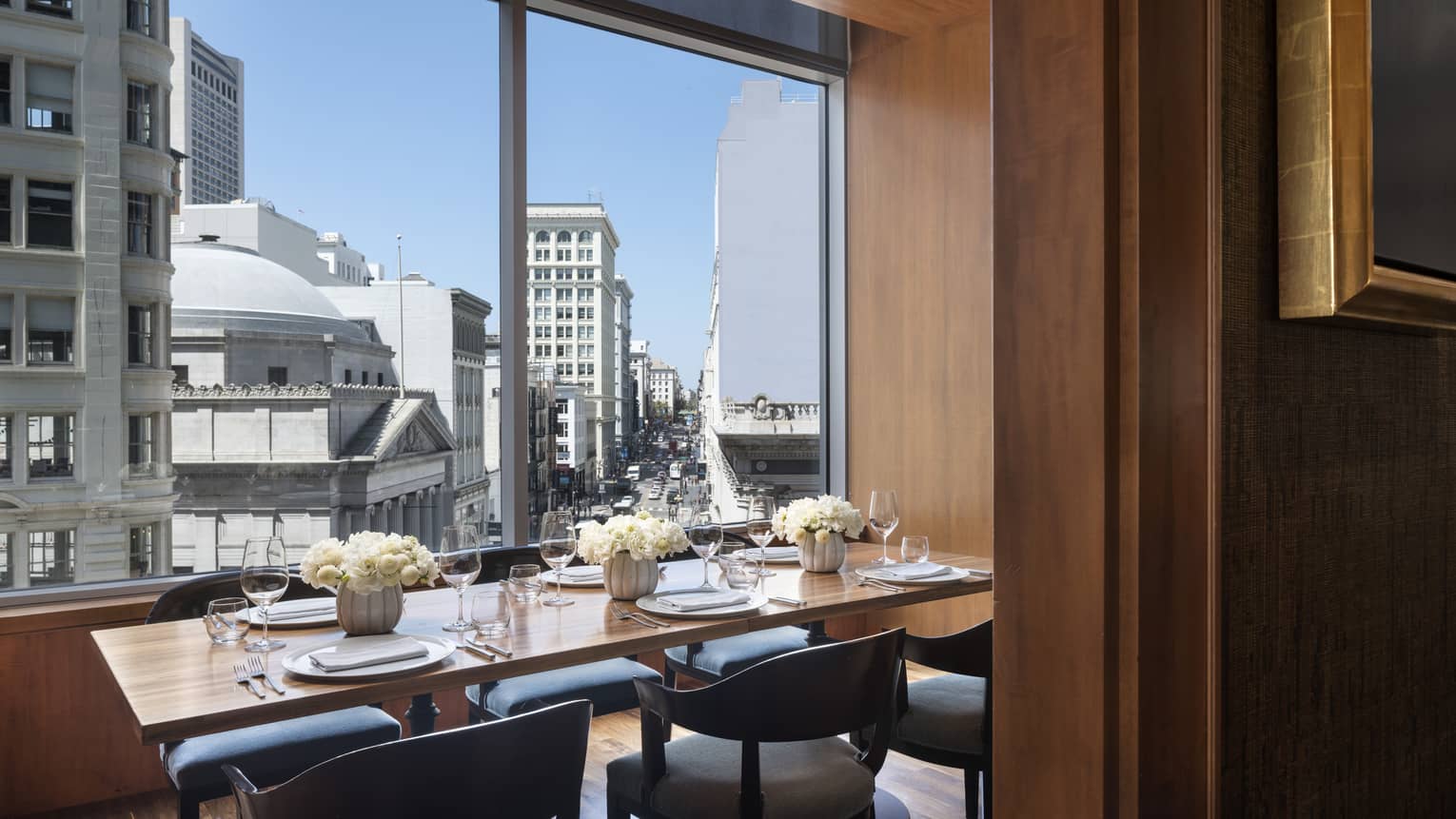 Private dining table with fresh white flowers by sunny window with San Francisco city view 