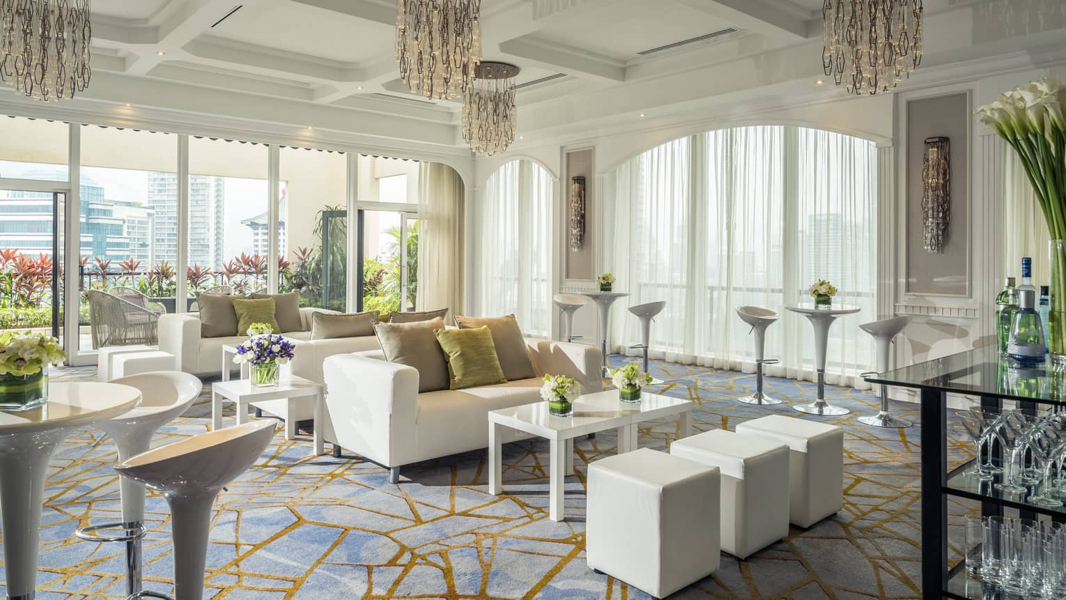 Penthouse room with floor to ceiling windows, contemporary white furniture, chandeliers, flowers