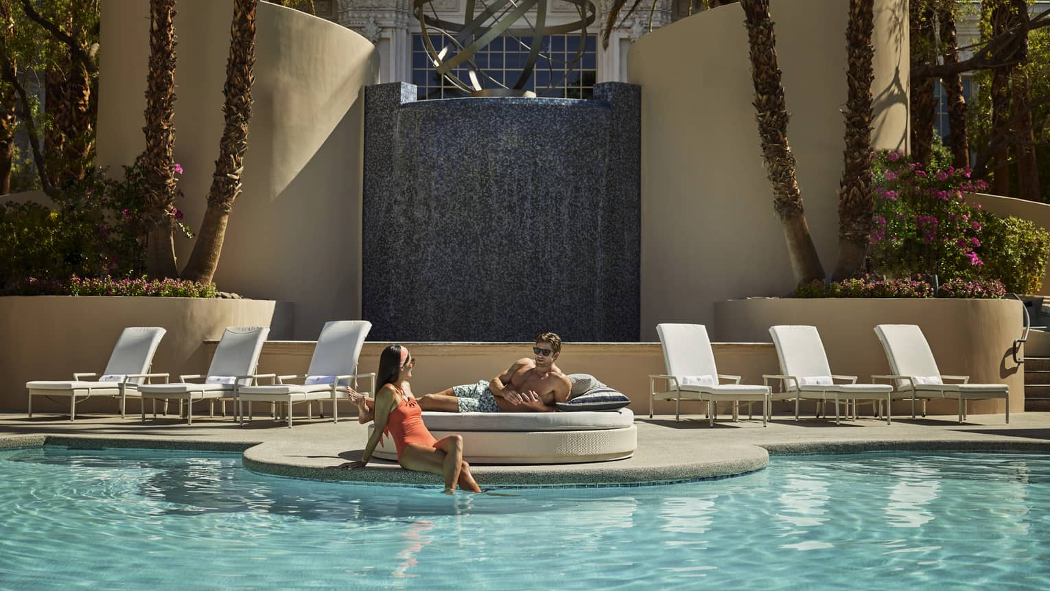 A man and woman relaxing near an outdoor pool.