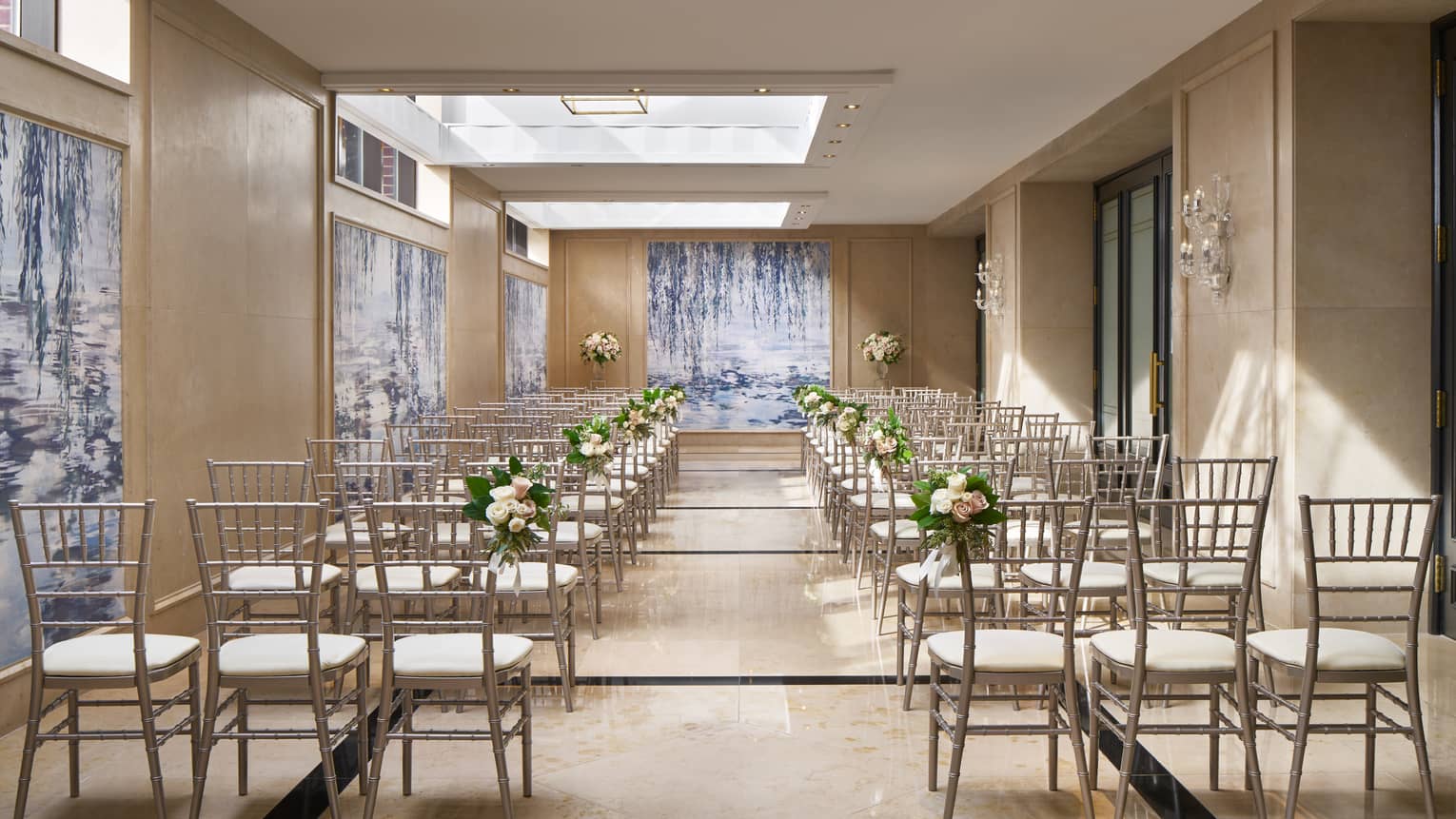 Rows of chairs under the ample skylights of Dumbarton Conservatory, decorated with wedding flowers.