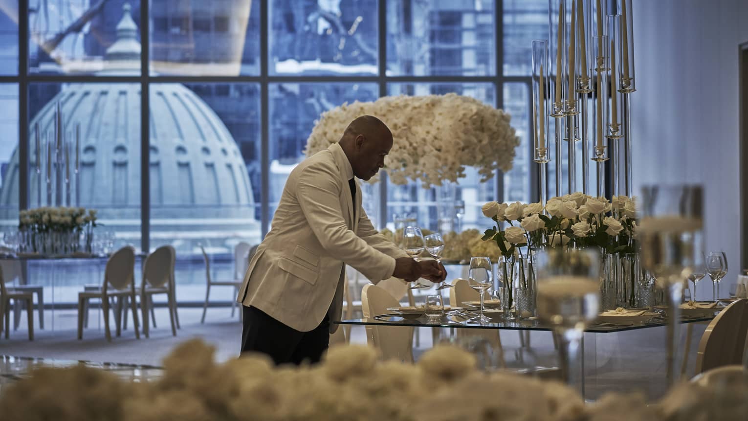 A four seasons staff does the finishing touches on a circular table in the ballroom, decorated with extravagant white florals
